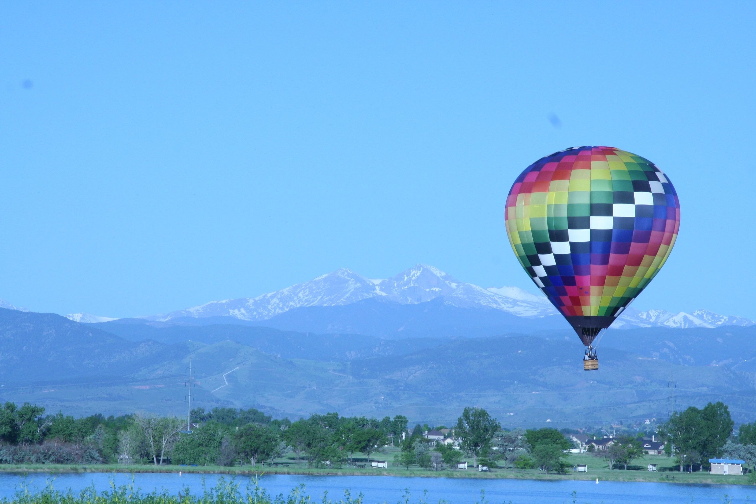 Hot air balloon over the Colorado foothills with snow-capped mountains on the horizon