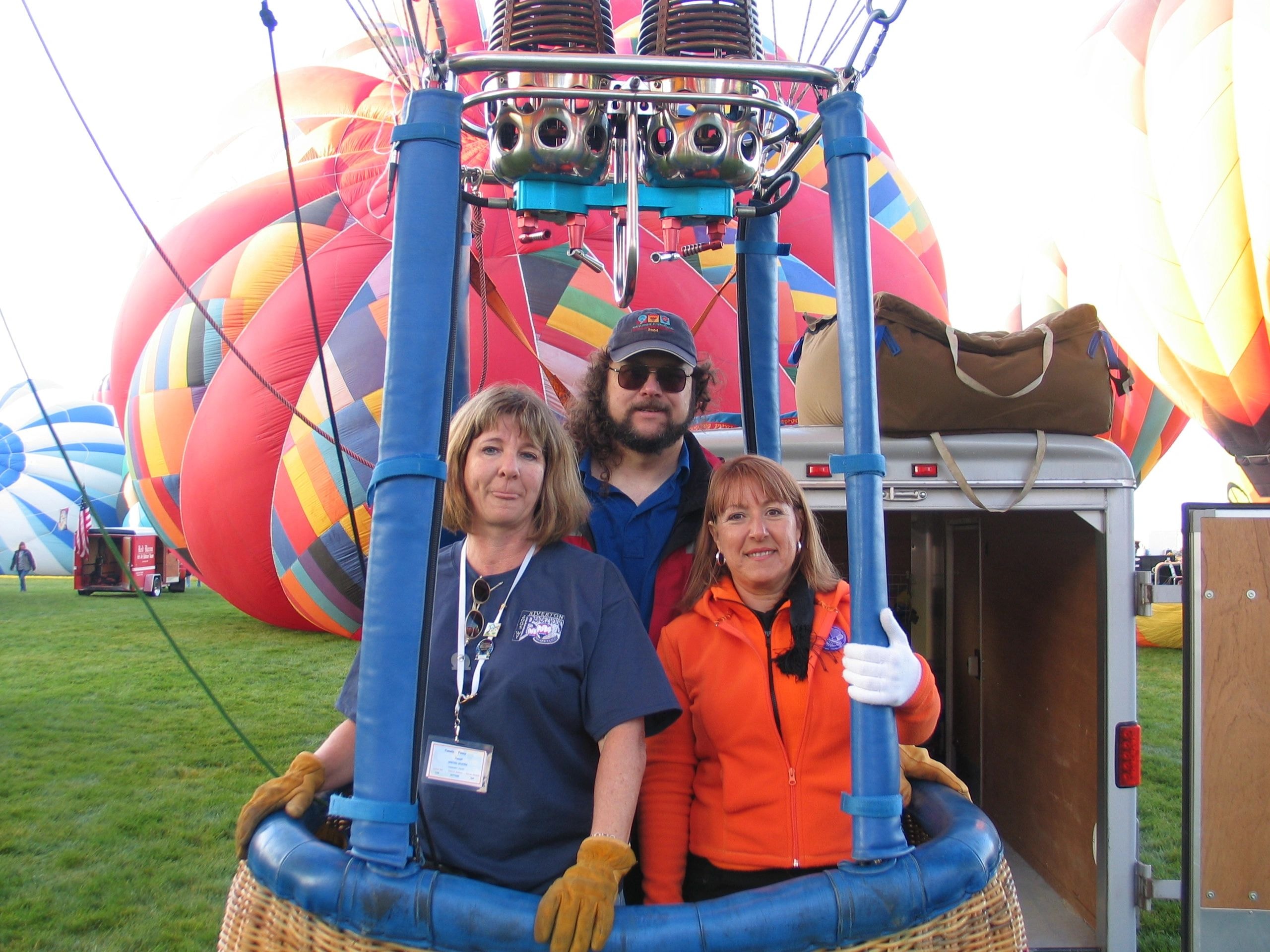 Three people posing inside hot air balloon basket